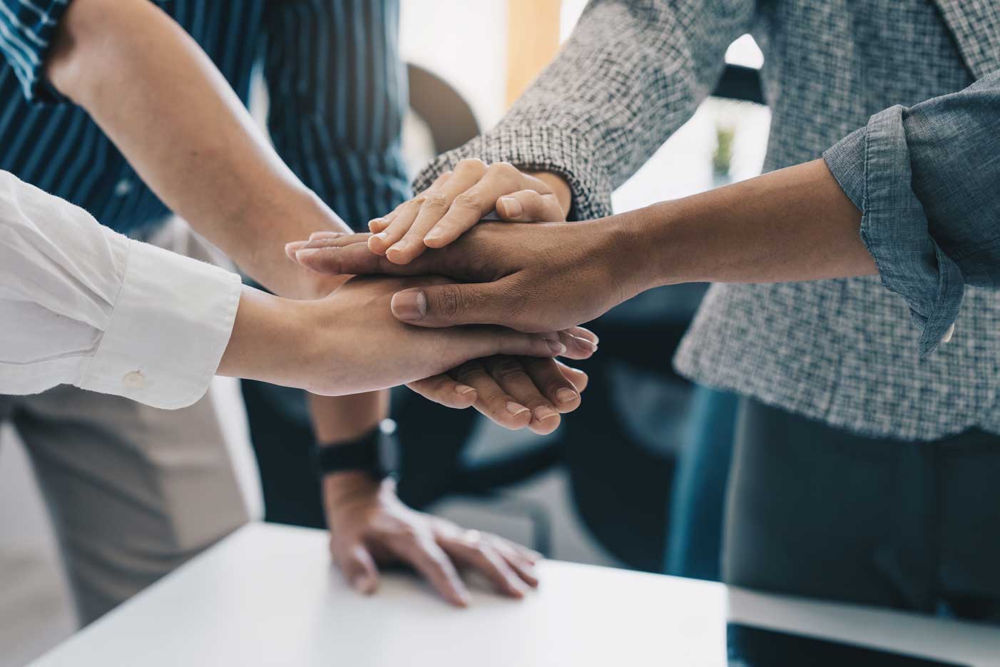 People in a circle with hands meeting in the center, stacked on top of each other